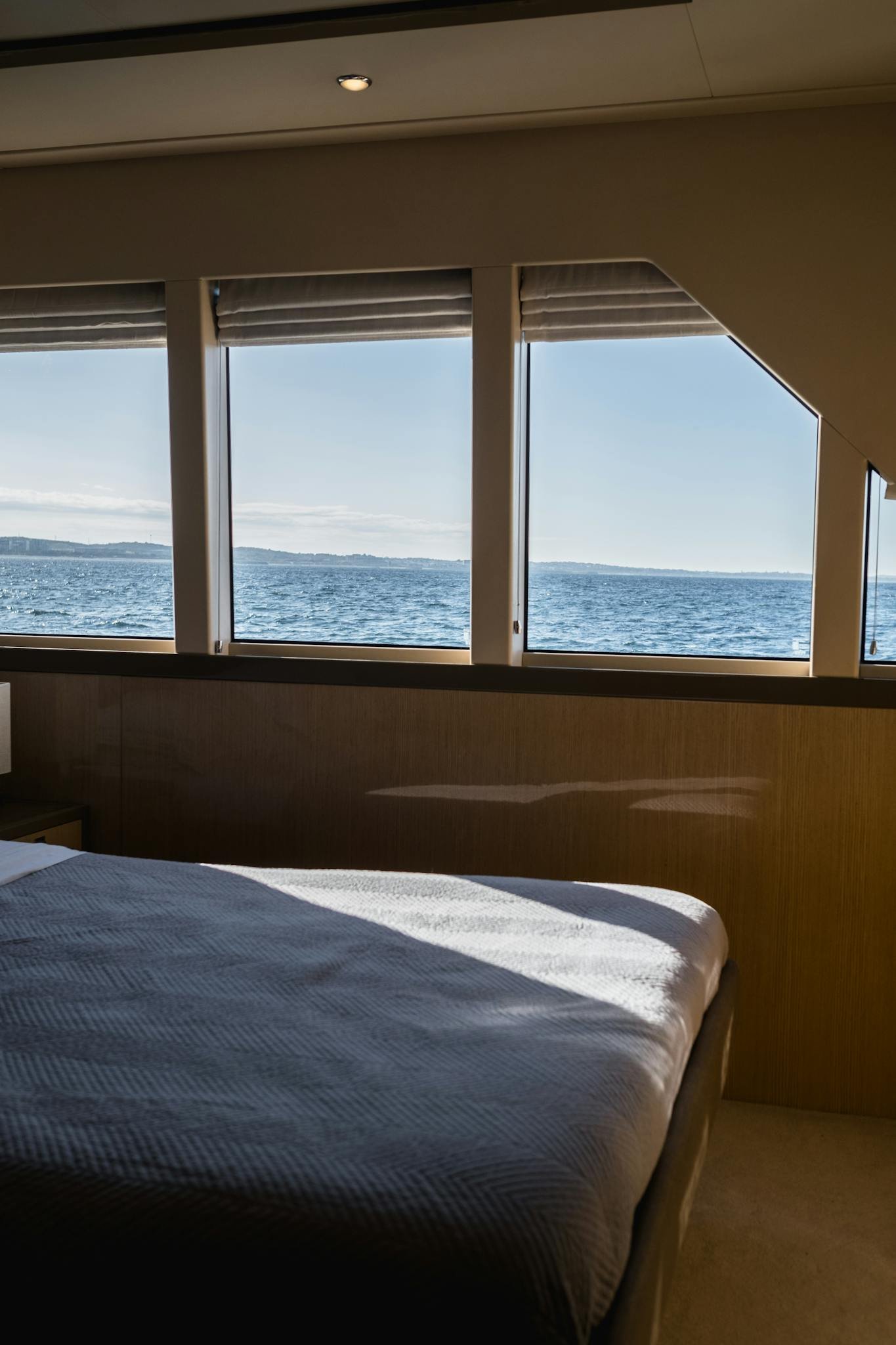Elegant yacht bedroom interior with stunning ocean view through large windows.